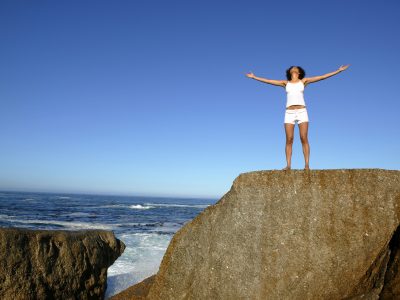 Woman standing on cliff by seashore